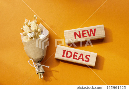 New ideas symbol. Concept word New ideas on wooden blocks. Beautiful orange background with bouquet of flowers. Business and New ideas concept. Copy space 135961325