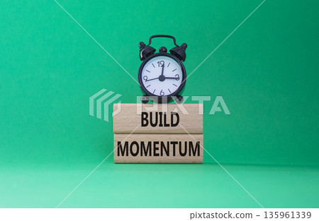 Build momentum symbol. Wooden blocks with words Build momentum. Beautiful green background with alarm clock. Business and Build momentum concept. Copy space. 135961339