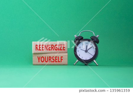Reenergize yourself symbol. Concept words Reenergize yourself on wooden blocks. Beautiful green background with alarm clock. Mindfulness and Reenergize yourself concept. Copy space. 135961359