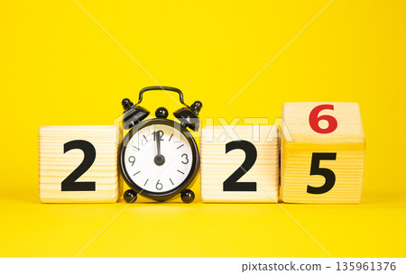2026 New Year symbol. Businessman turns wooden cube and changes Year 2025 to 2026. Beautiful yellow background with Alarm clock. Copy space. Business and 2026 happy new year concept 2026 New Year symbol. Businessman turns wooden cube and changes Year 2025 to 2026. Beautiful yellow background with Alarm clock. Copy space. Business and 2026 happy new year concept 135961376