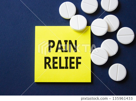 Pain Relief symbol. Concept word Pain Relief on yellow note. Beautiful deep blue background with pills. Medicine and Pain Relief concept. Copy space 135961433
