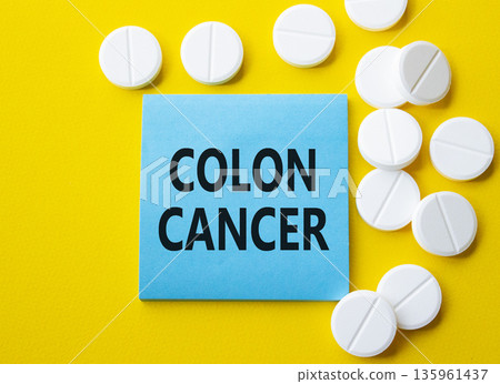 Colon Cancer symbol. Concept word Colon Cancer on blue note. Beautiful yellow background with pills. Medicine and Colon Cancer concept. Copy space Colon Cancer symbol. Concept word Colon Cancer on blue note. Beautiful yellow background with pills. Medicine and Colon Cancer concept. Copy space 135961437