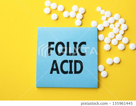 Folic acid symbol. Concept word Folic acid on blue note. Beautiful yellow background with pills. Medicine and Folic acid concept. Copy space 135961445