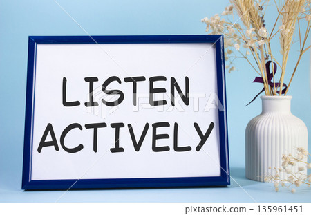 Listen actively symbol. Concept words Listen actively on beautiful wooden picture frame. Beautiful light blue background with flower vase. Business and Listen actively concept. Copy space. 135961451