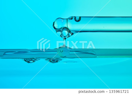 Pipette dripping clear serum into blue liquid Pipette dripping clear serum into blue liquid 135961721