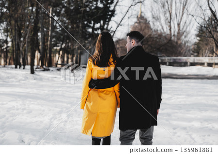 Couple walks together in snowy park while enjoying winter day Couple walks together in snowy park while enjoying winter day 135961881