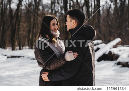 Couple enjoying a winter day together in a snowy forest setting Couple enjoying a winter day together in a snowy forest setting 135961884