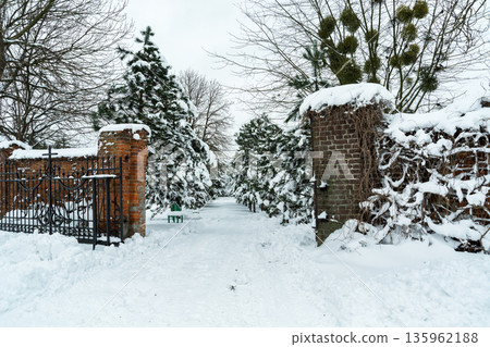 An open gate with a cross towards a snow-covered park with trees, Chelm, Poland An open gate with a cross towards a snow-covered park with trees, Chelm, Poland 135962188