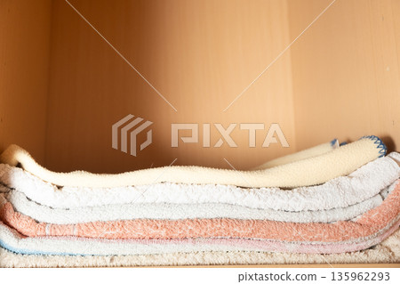 Perfectly folded white and colored towels on wooden shelf for linen closet organization 135962293