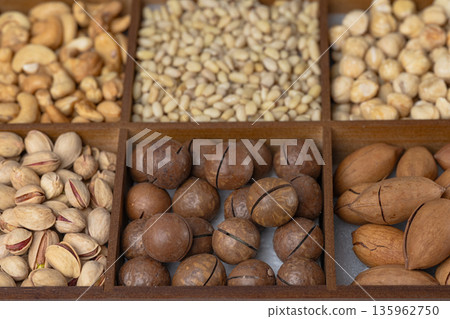 Mixed nut background: pine nuts, pistachios, cashews, almonds, hazelnuts, peanuts, macadamia, pecans, 135962750