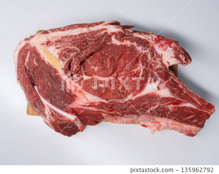Raw bone-in ribeye steak isolated on white background. Fresh beef meat cut with marbling top view. Uncooked food ingredient for barbecue or grill Raw bone-in ribeye steak isolated on white background. Fresh beef meat cut with marbling top view. Uncooked food ingredient for barbecue or grill 135962792