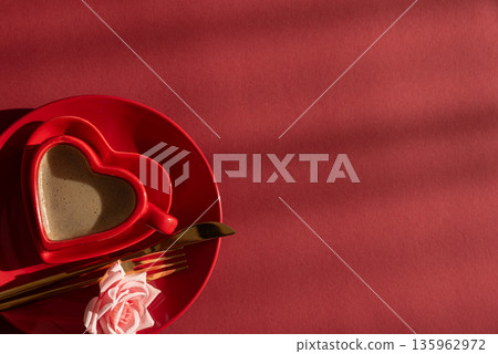 Heart Shaped Coffee Cup with Rose. Romantic Valentines Day Table Setting on Red Background Heart Shaped Coffee Cup with Rose. Romantic Valentines Day Table Setting on Red Background 135962972