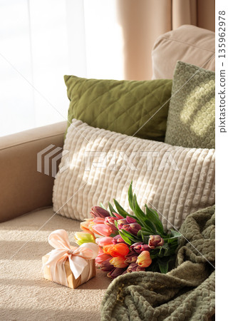 Tulip Bouquet and Gift Box on Cozy Sofa. Warm Spring Stylelife with Sunlight Tulip Bouquet and Gift Box on Cozy Sofa. Warm Spring Stylelife with Sunlight 135962978
