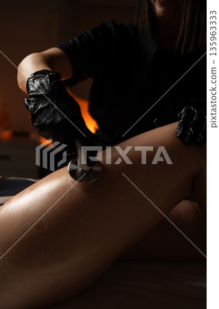Professional radiofrequency RF lifting procedure performed on the body in a modern cosmetic spa environment. 135963333