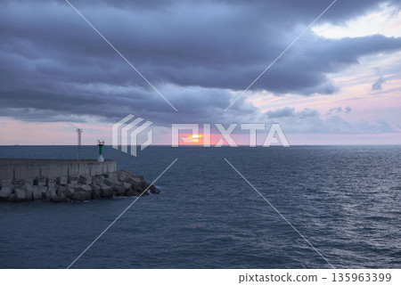 Sunrise from green lighthouse on maritime breakwater Sunrise from green lighthouse on maritime breakwater 135963399