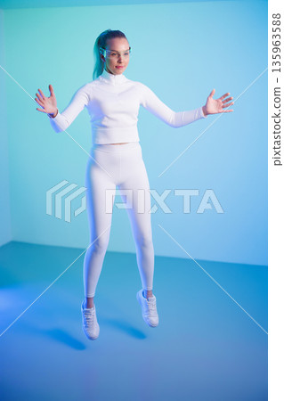 Woman in smartglasses jumping against blue background Woman in smartglasses jumping against blue background 135963588