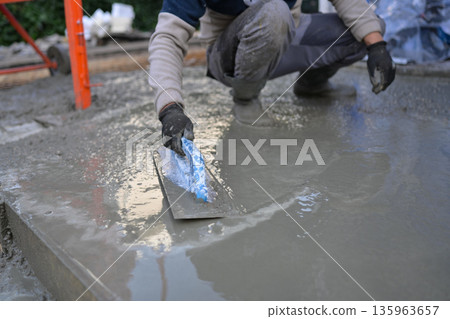 Construction Worker Smoothing Wet Concrete with Trowel 135963657