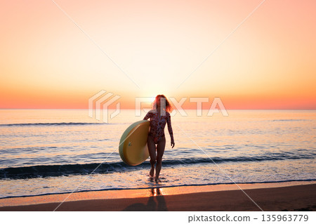 Young woman standing on beach with paddle sup boards during summer vacation 135963779