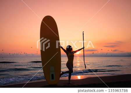 Young woman standing with paddle sup boards by the sea during summer vacation 135963786