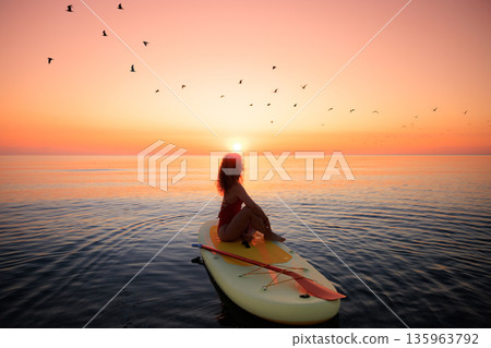 Young woman walking on stand up paddle sup boards by the sea during summer vacation 135963792