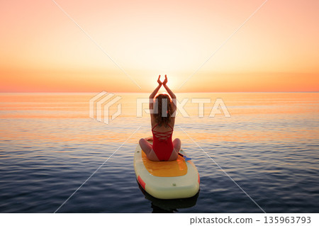 Young woman walking on stand up paddle sup boards by the sea during summer vacation Young woman walking on stand up paddle sup boards by the sea during summer vacation 135963793