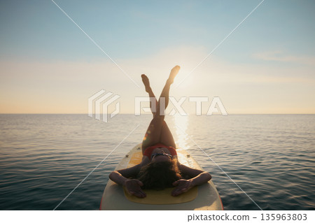 Young woman walking on stand up paddle sup boards by the sea during summer vacation 135963803
