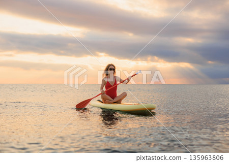 Young woman walking on stand up paddle sup boards by the sea during summer vacation 135963806