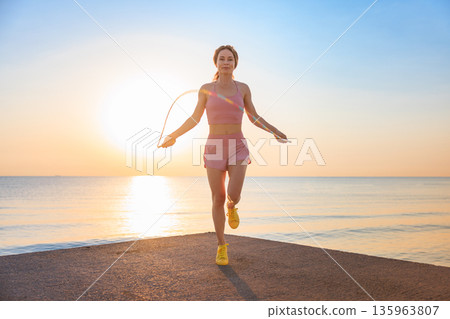Fit woman jumping rope at the beach during summer vacation 135963807
