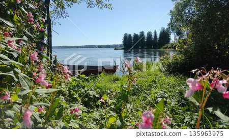 The boat is moored in the water near the forest. 135963975
