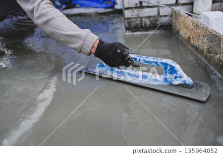 Construction Worker Smoothing Wet Concrete with Trowel Construction Worker Smoothing Wet Concrete with Trowel 135964052