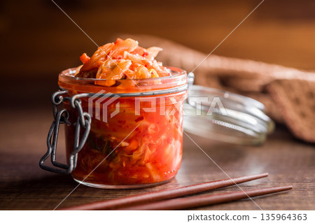 Fermented cabbage. Kimchi. Korean food in jar on wooden table. 135964363