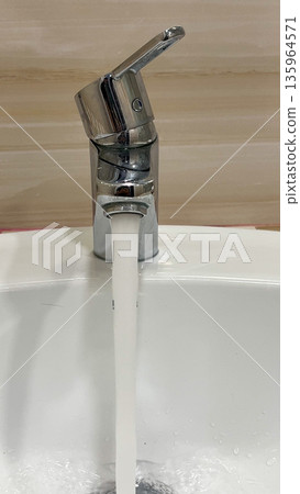 Water flows from an open tap in the bathroom. Bathroom and toilet, utilities  135964571