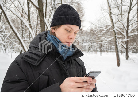 Young man using smartphone in snowy forest 135964790