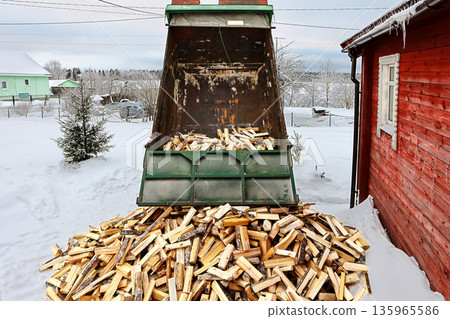 Delivery of split logs to house with wood stove heating, dump truck emptied bed unloading logs onto snow. Delivery of split logs to house with wood stove heating, dump truck emptied bed unloading logs onto snow. 135965586