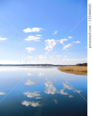 A perfect mirror reflection of clouds in the calm water of a lake A perfect mirror reflection of clouds in the calm water of a lake 135966085