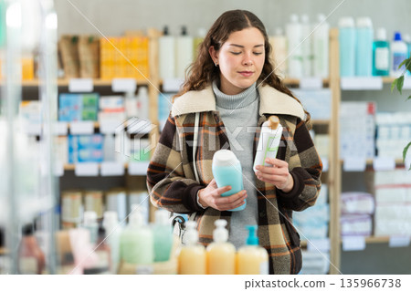 Young woman chooses shampoo at pharmacy Young woman chooses shampoo at pharmacy 135966738