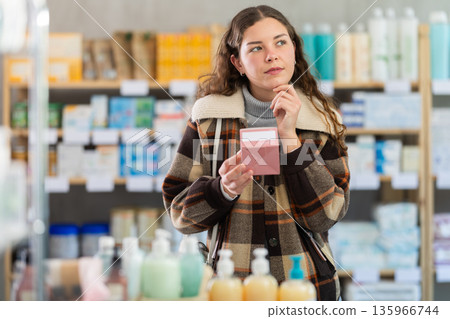 Girl in winter clothes looking for medicine in pharmacy 135966744