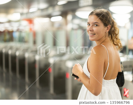 Positive young girl passing through terminal in subway station Positive young girl passing through terminal in subway station 135966796