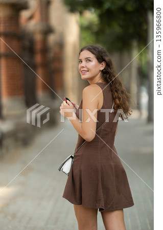 Back view of positive young woman watching smartphone walking in street of Barcelona, lifestyle technology concept Back view of positive young woman watching smartphone walking in street of Barcelona, lifestyle technology concept 135966800