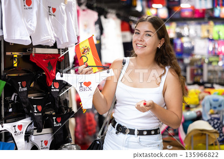 Female buyer holds in hands hanger with womens thongs decorated with inscription Barcelona 135966822