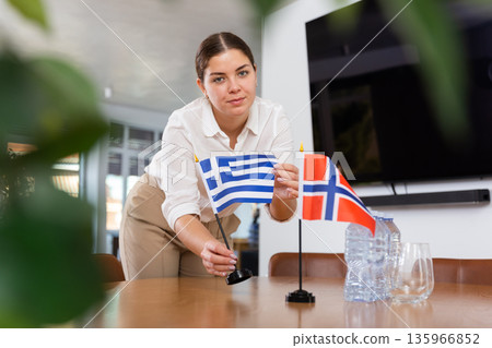 girl assistant prepares conference room for international negotiations between representatives of Norway and Greece girl assistant prepares conference room for international negotiations between representatives of Norway and Greece 135966852