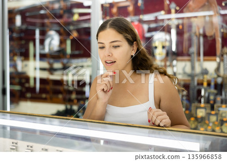 Traveler girl examines goods in glass shop window of souvenir shop Traveler girl examines goods in glass shop window of souvenir shop 135966858