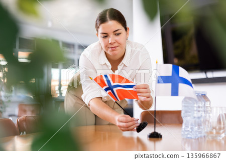 female assistant prepares conference room for diplomats of Finland and Norway female assistant prepares conference room for diplomats of Finland and Norway 135966867