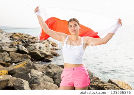 Young woman on coast posing with flag of Poland 135966876