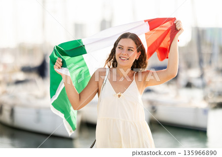Woman waving Italian flag against seaport and yachts Woman waving Italian flag against seaport and yachts 135966890
