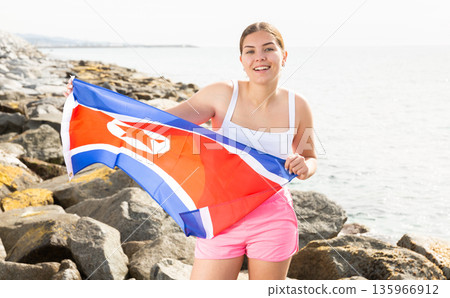 Young woman on coast posing with flag of North Korea Young woman on coast posing with flag of North Korea 135966912