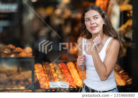 Young female tourist exploring traditional pastry in bakery window 135966980