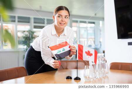 Young lady sets miniatures flags of Canada and Iraq before international negotiations Young lady sets miniatures flags of Canada and Iraq before international negotiations 135966993