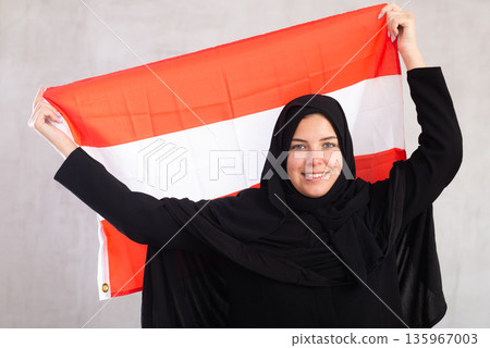 Happy young woman dressed in traditional islamic clothes with austrian flag 135967003