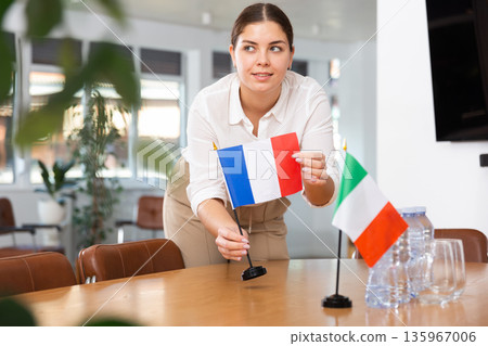 Employee of delegation prepares negotiating table - sets up flag of Italy and France Employee of delegation prepares negotiating table - sets up flag of Italy and France 135967006